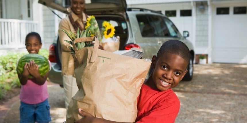 family-happily-removing-healthy-groceries-from-van-trunk