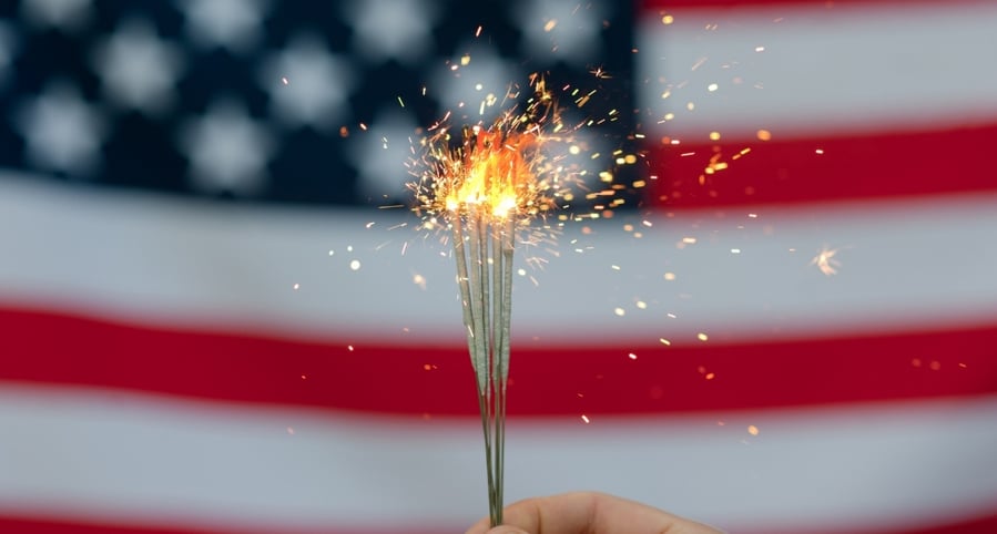 lit-sparkler-held-in-front-of-american-flag