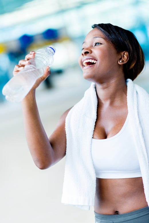 Gym woman hydrating drinking a bottle of water