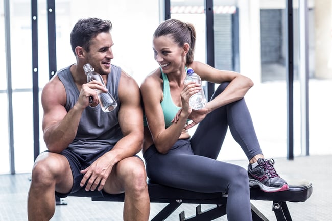Muscular couple discussing on the bench and holding water bottle-3