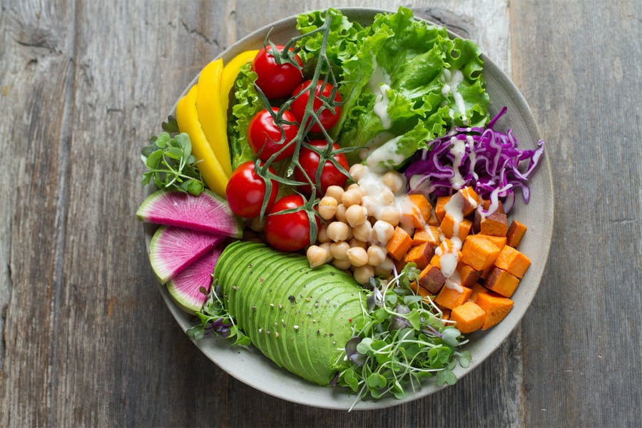 fresh vegetable salad with chickpeas and raw veggies with dressing in bowl