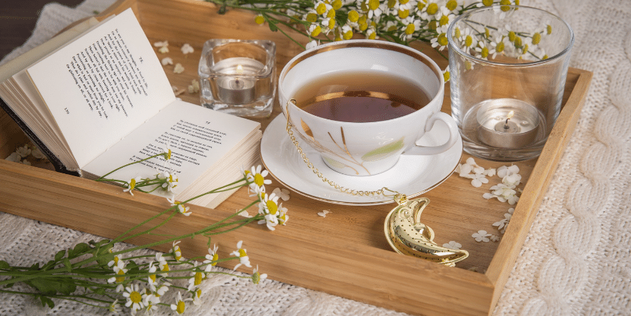 chamomile-tea-on-wooden-serving-tray-with-flowers-moon-and-book