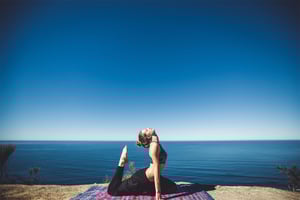 Woman staying physically fit and taking care of mental health during quarantine by doing yoga outside.